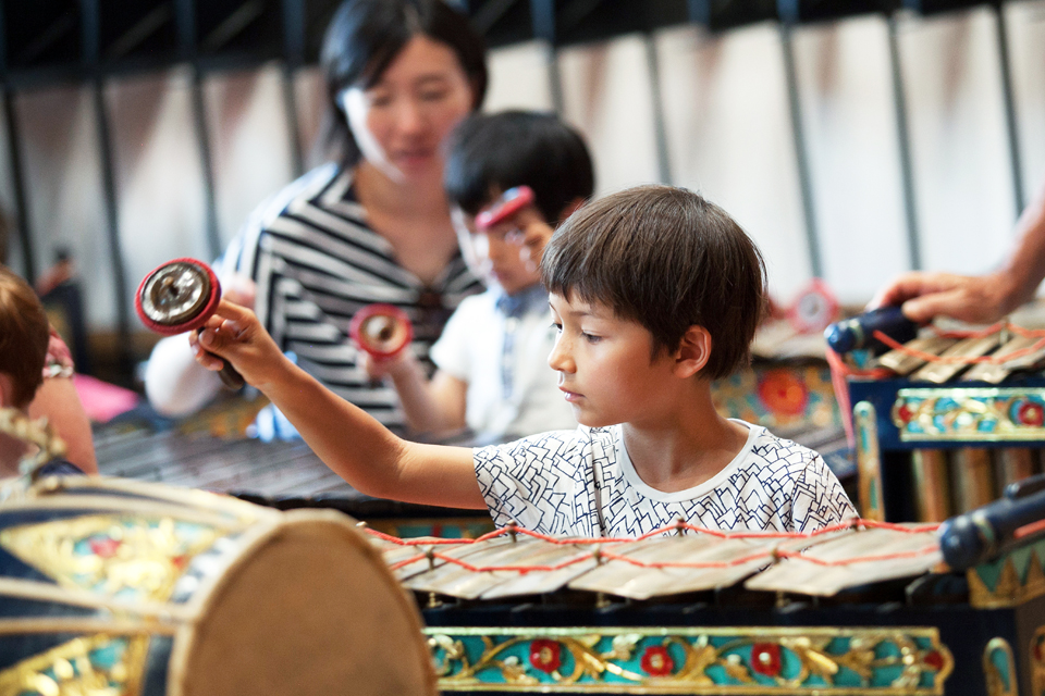 A boy looking at a percussion instrument and performing it.